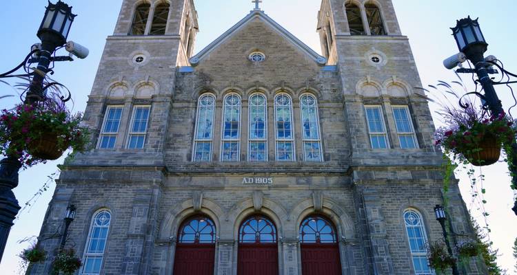 Stone facade of a historic twin-tower church with stained-glass windows against a clear blue sky