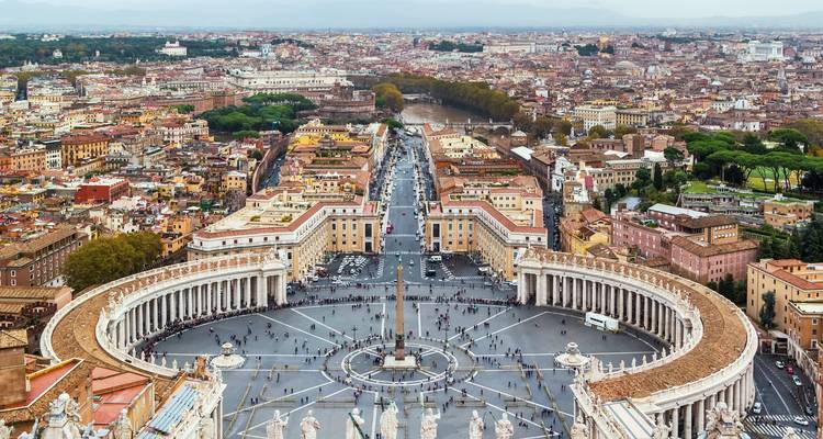 La place Saint-Pierre et ses colonnades majestueuses vues d'en haut avec Rome s'étendant au-delà.