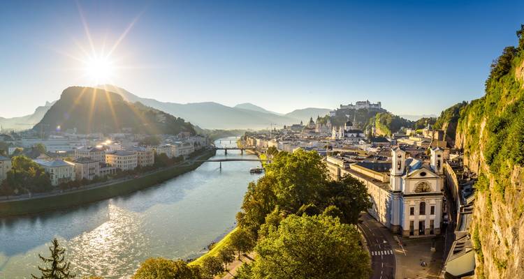 Lever de soleil sur Salzbourg avec la forteresse et la vieille ville se reflétant dans la rivière Salzach.