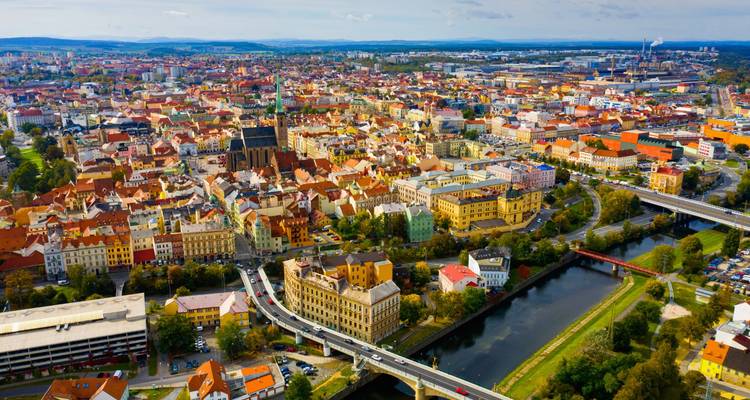 Panorama aéreo colorido de la ciudad de Pilsen con la aguja de la catedral, el río y la red de carreteras en un día soleado.