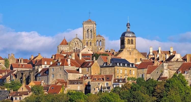 Charming hilltop village with stone rooftops and twin church towers under clear sky in Vézelay.