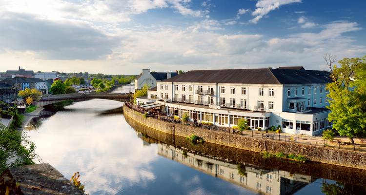 Charming riverside town with hotel buildings reflected in calm water and stone bridge