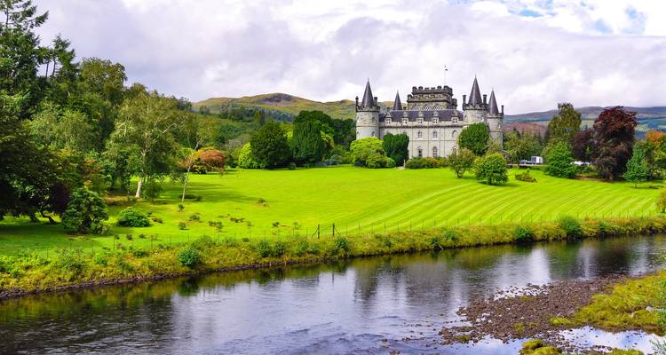 Elegant Inveraray Castle framed by lush green lawn and river, set amid gentle hills