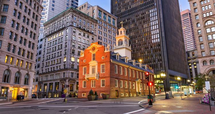 La histórica Casa del Estado de ladrillos rojos enmarcada por los rascacielos modernos de Boston bajo la luz del atardecer temprano.