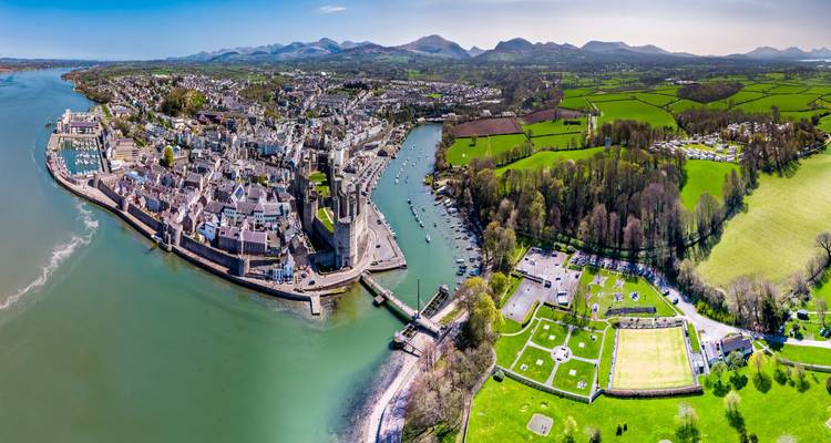 Stunning aerial view of Caernarfon town, castle and green Welsh countryside backed by mountains
