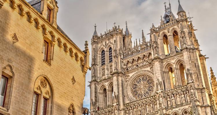 Ornate gothic façade of Amiens Cathedral with intricate stone carvings in warm light