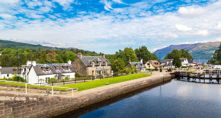 Picturesque canal locks and stone cottages beside a peaceful waterway leading toward distant hills.