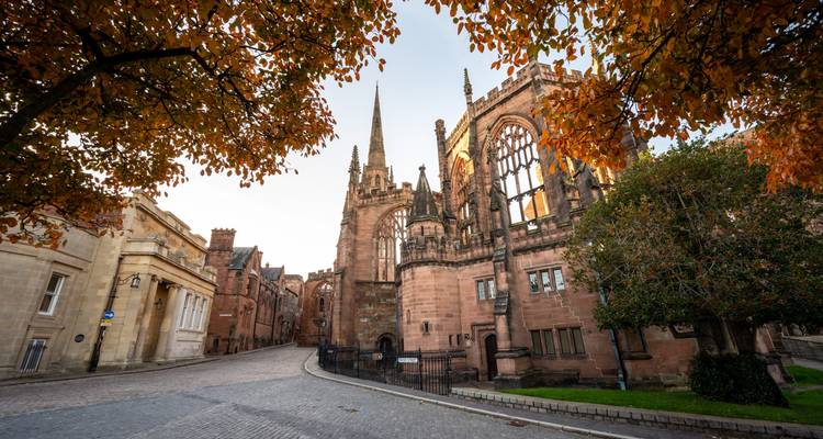 Historic red-sandstone cathedral ruins framed by golden autumn leaves