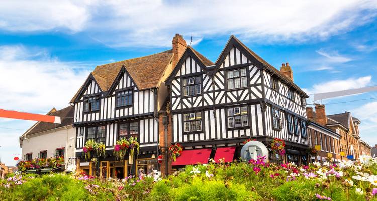 Colorful flower beds in front of timber-framed Tudor buildings on a sunny day in Stratford-upon-Avon