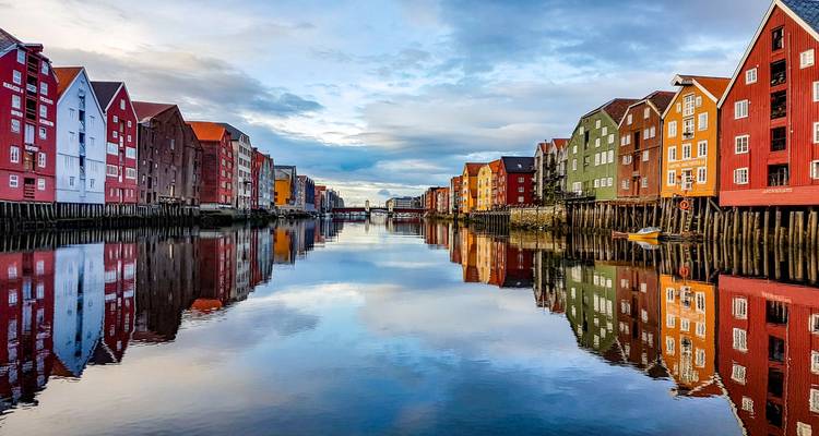 Colourful wooden warehouses line both sides of Trondheim’s Nidelva River mirrored perfectly in the water.