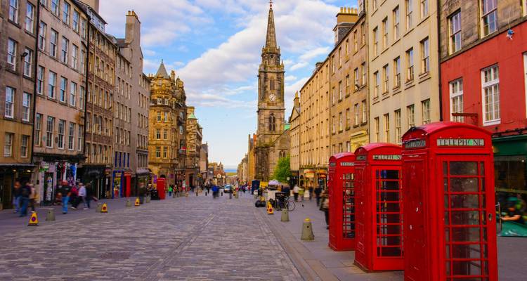 Bustling Royal Mile in Edinburgh with historic stone buildings and iconic red telephone boxes.