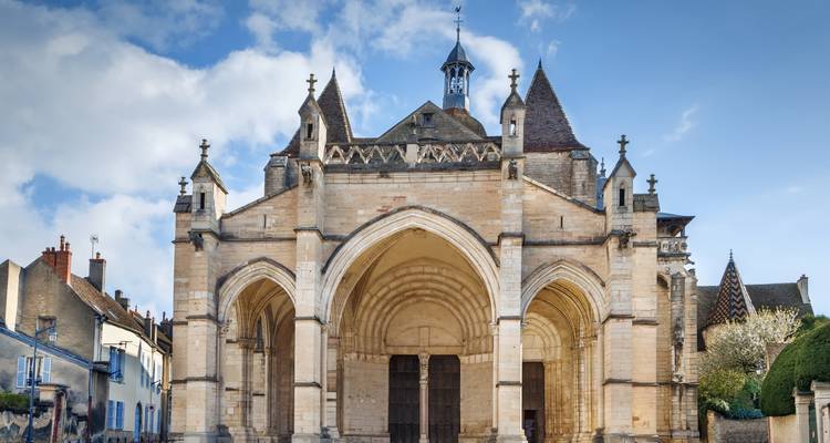 Façade en pierre de la Collégiale Notre-Dame à Beaune illuminée par la douce lumière du matin.
