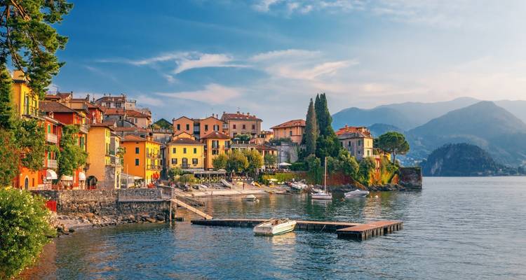 Charming pastel village of Varenna on Lake Como with mountains in hazy light.
