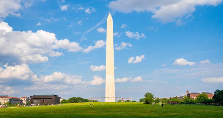 Het Washington Monument torent uit boven het groene gazon van het National Mall onder een helder blauwe lucht met hier en daar wat wolken.