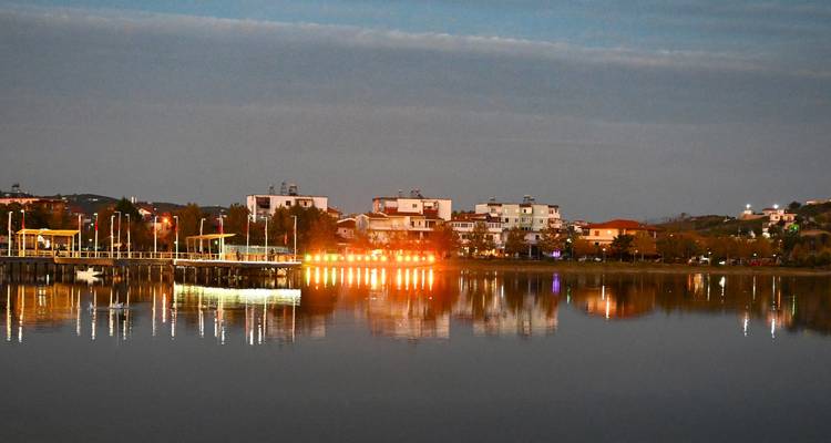Evening view of a lakeside town with lights reflecting on calm water.