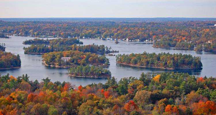 Aerial scene of autumn-colored Thousand Islands dotting a calm river-lake landscape.