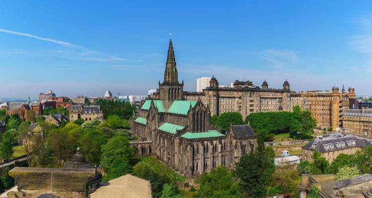 Panoramic daytime view of Glasgow Cathedral surrounded by green parks and city buildings.