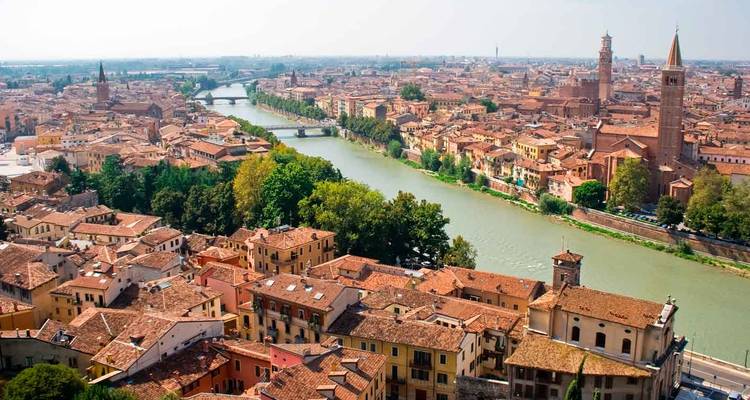 Vue panoramique vaste d'une ville aux toits de terre cuite divisée par un fleuve sinueux.