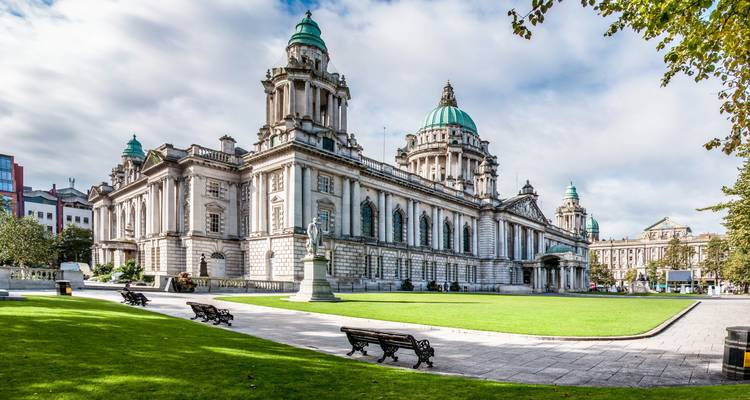 L'impressionnant Belfast City Hall avec ses dômes verts encadrés par des arbres et illuminés par la lumière matinale brillante.