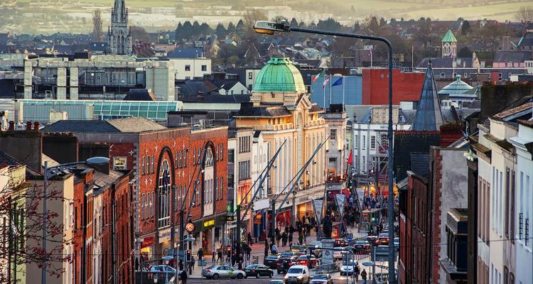 Scène urbaine animée du centre-ville de Cork avec des bâtiments historiques, de la circulation et des passants.