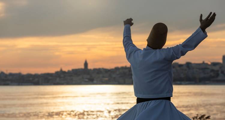 Silhouette of a whirling dervish raising arms toward a golden sunset over Istanbul’s skyline and water.