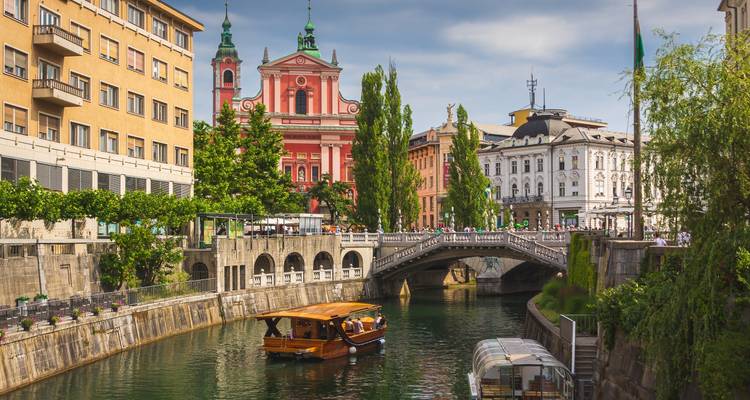 Picturesque canal in Ljubljana with boats, bridges and colorful facades.