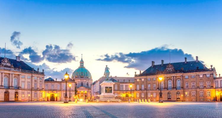 Wide cobblestone square of Amalienborg with the Marble Church dome at twilight.