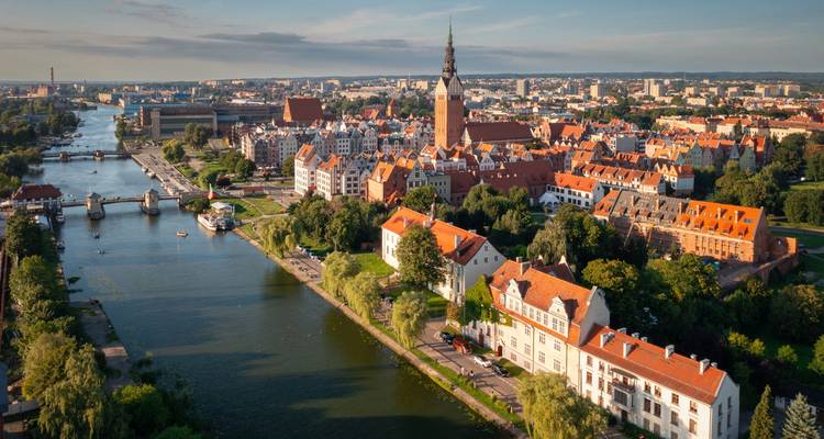 Historic red-roofed town spreads along a winding river beneath a tall church steeple.