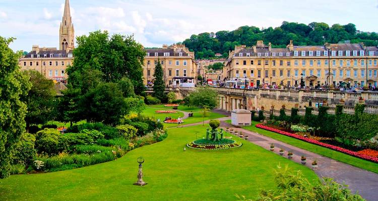 Formal gardens and Georgian terraces of Bath with a spired church rising beyond the lawns.