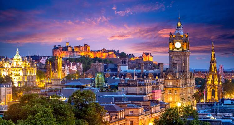 Colourful sunset over Edinburgh with illuminated castle and Balmoral Clock Tower dominating the skyline.