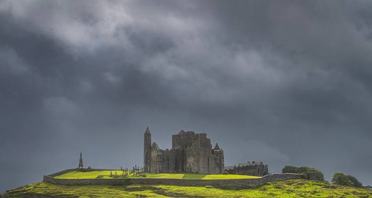 Le Rocher de Cashel perché sur une colline verdoyante sous des nuages d'orage dramatiques.