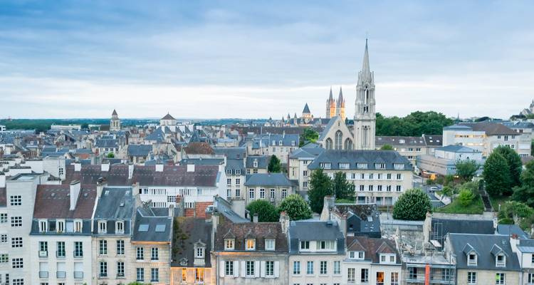 Vue aérienne du paysage urbain de Tours avec des églises et des toits s'étendant jusqu'à l'horizon sous une lumière douce.