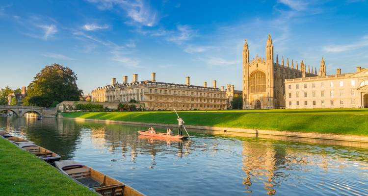 Punting boat glides along the River Cam beside King’s College Chapel and manicured lawns in golden light.