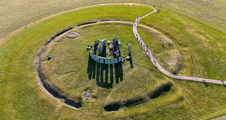 Aerial perspective of Stonehenge casting long shadows across the surrounding grassy plain.