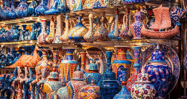 Des étagères débordant de poteries turques aux couleurs vives et de vases dans une boutique de marché.