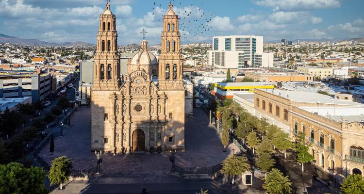 Dronefoto van de Chihuahua Kathedraal die het centrale plein domineert met stadsgezicht op de achtergrond