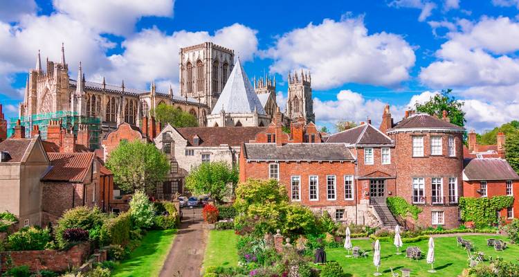 Historic York skyline dominated by York Minster above charming red-brick houses and leafy gardens.