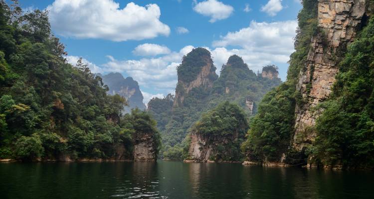 Tranquil lake surrounded by dramatic karst peaks and lush forest in Zhangjiajie.
