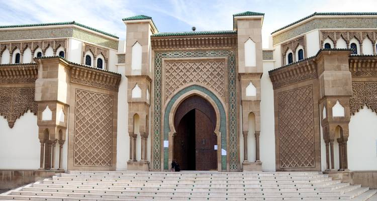 Grand arched gateway of the Royal Palace in Rabat with intricate geometric tilework and shallow steps leading up.