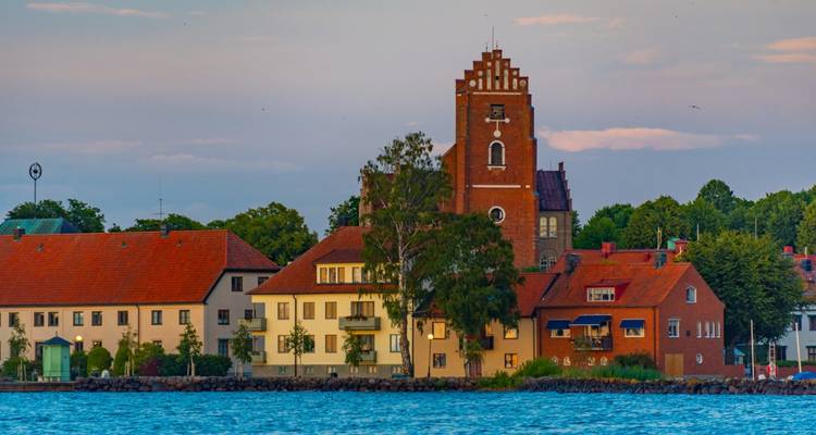 Small Swedish lakeside town with brick church tower and traditional houses at dusk