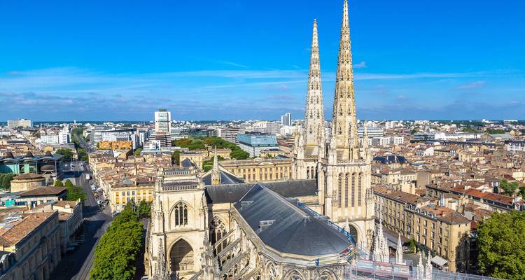 The twin spires of Bordeaux Cathedral rise above the historic cityscape on a bright day.