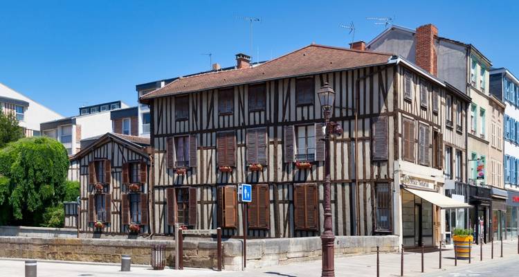 Half-timbered medieval houses line a quiet street under clear blue skies.