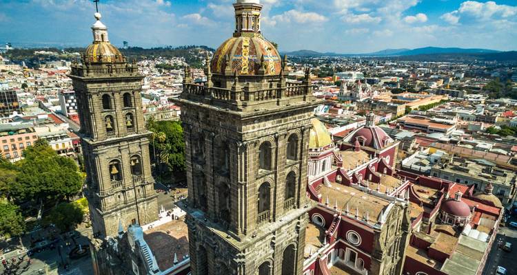 Gros plan aérien des tours ornées de la Cathédrale de Puebla surplombant la ville qui s'étend en contrebas.