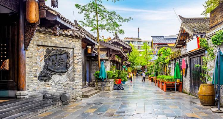 Encantadora calle peatonal antigua con edificios de ladrillo tradicionales y sombrillas coloridas en Chengdu.