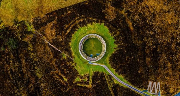 Aerial of a perfectly circular ancient stone ringfort surrounded by moorland.