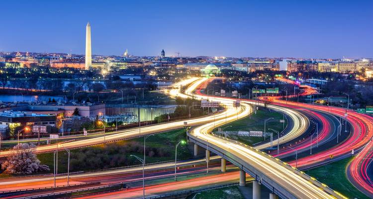 Lange-sluitertijd nachtfoto van snelwegen die zich naar het centrum van Washington DC kronkelen met het Washington Monument in de verte.