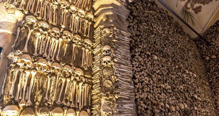 Mur intérieur de la Chapelle des Os d'Évora tapissé de crânes humains et d'os arrangés créant une texture sinistre.