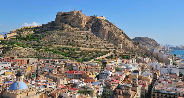 El colorido casco antiguo de Alicante acurrucado bajo el Castillo de Santa Bárbara y las áridas lomas.