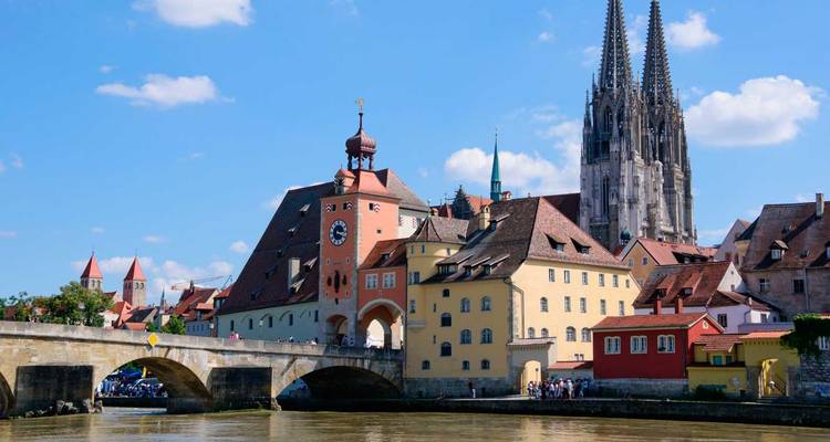 Pont de pierre et bâtiments médiévaux colorés le long du Danube avec la cathédrale de Ratisbonne qui s'élève majestueusement.