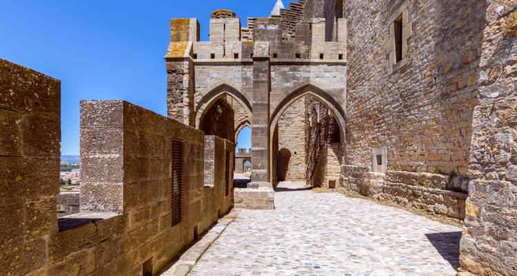 Passage en pierre avec des arches pointues le long des murs fortifiés de Carcassonne par une belle journée d'été ensoleillée.